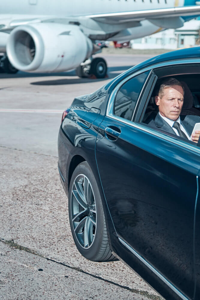 Executive traveller in a car with aircraft in view – the reality of early starts and tight turnarounds
